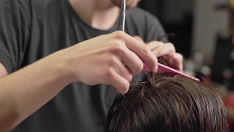 close-up of a haircut with scissors and fingers holding a comb