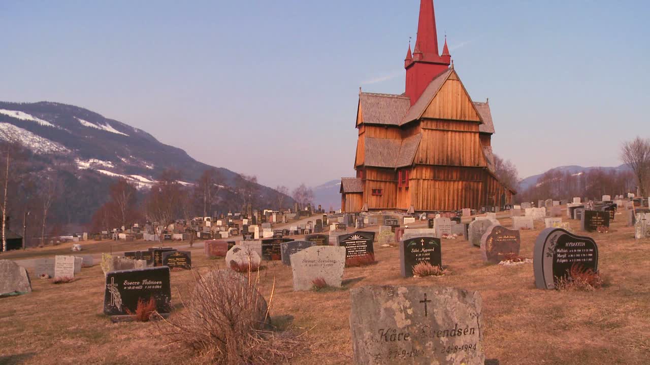 un cementerio frente a una antigua iglesia de madera en noruega