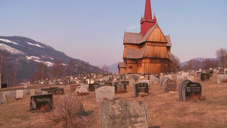 um cemitério em frente a uma velha igreja de madeira na noruega