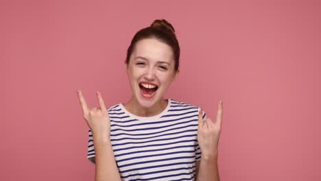 una mujer encantada mostrando señales de mano de rock and roll, gritando y gestando con heavy metal, música rock.