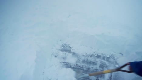 man scraping ground by a shovel covered with thick snow in trondheim, norway