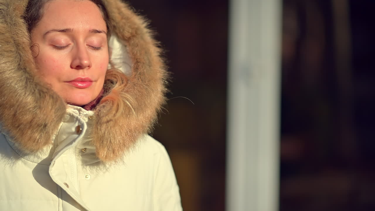 A woman enjoys a moment of mindfulness meditation outdoors during winter. Sunlight warms her face as she finds calmness, surrounded by nature. This peaceful scene invites serenity and reflection