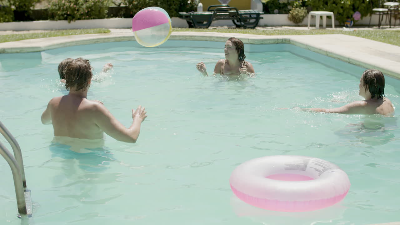 여름날 수영장에서 공놀이를 하는 백인 가족