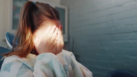 a young girl covers her face in fear at the dentist's office