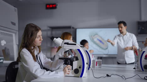 estudiantes en un laboratorio de ciencias usando microscopios