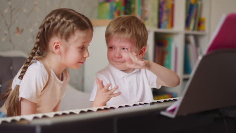 Boy-smiles-through-tears-and-shows-hands-to-sister-at-piano