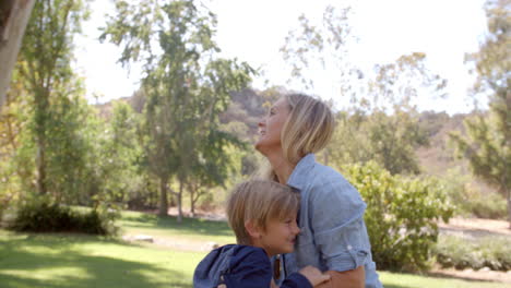 Mother-lifting-up-her-son-and-embracing-in-a-park