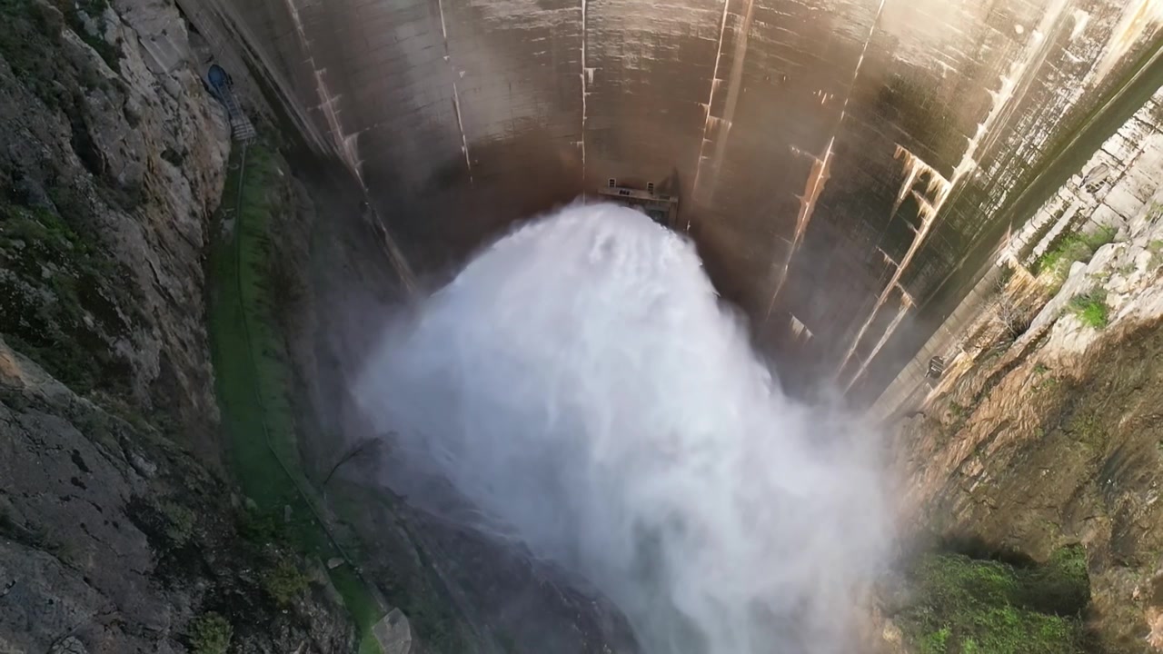 Diga che rilascia acqua. Vista aerea al rallentatore dello scarico dell'acqua dalla diga. Valvola Howell Bunger in funzione nella diga a volta. Bacino di Quentar. Spagna