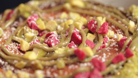 Pistachio-donut-being-decorated-close-up-dried-raspberry