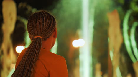 a girl looks at a dancing fountain in a park in the center of kharkiv