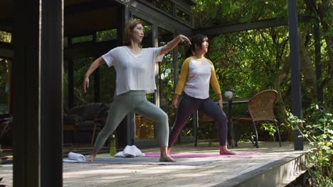 asian mother and daughter practicing yoga outdoors in garden