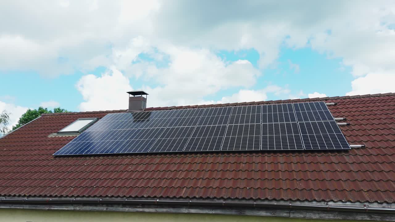 Solar panels installed on tiled roof of a residential house with cloudy sky, wide orbital shot