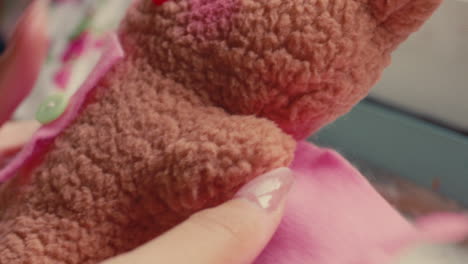 sewing a pink cloth onto a teddy bear