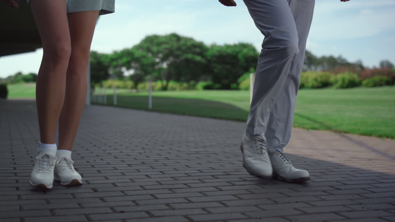 Golf players legs walking grass country club course on sunny summer morning.