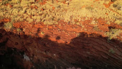 aerial rising pullback showing woman close to red cliffs of joffre falls gorge in karijini nation park at sunny day