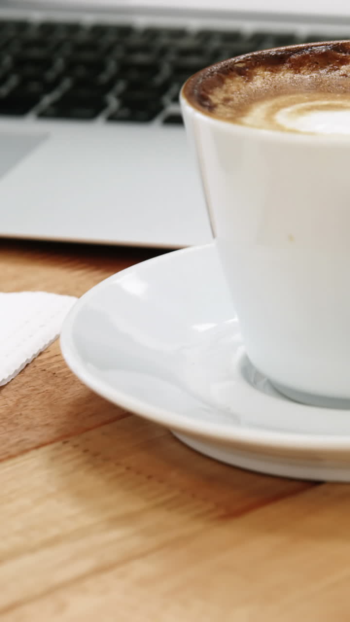 primer plano de una computadora portátil con una taza de café y una galleta dulce