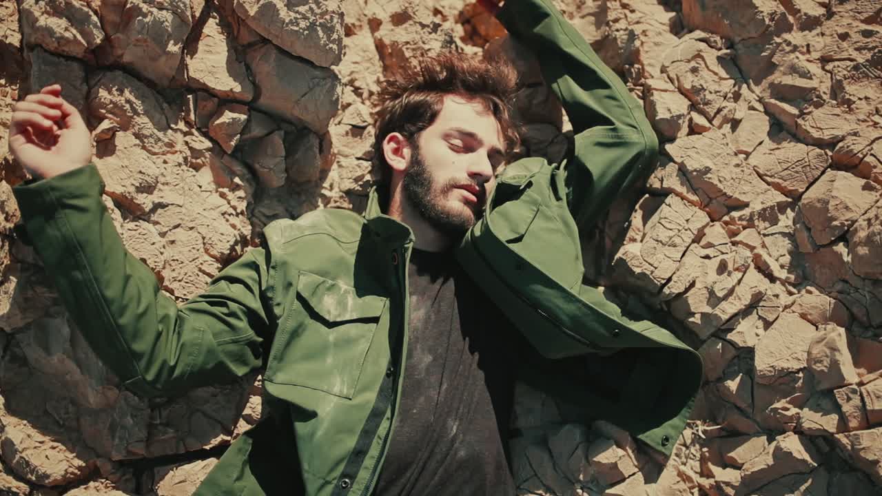 Top down view of lifeless Israeli man lying on dry rocky desert terrain