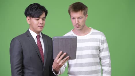 젊은 잘생긴 아시아 사업가와 젊은 스칸디나비아 사업가가 함께 일하고 있습니다.