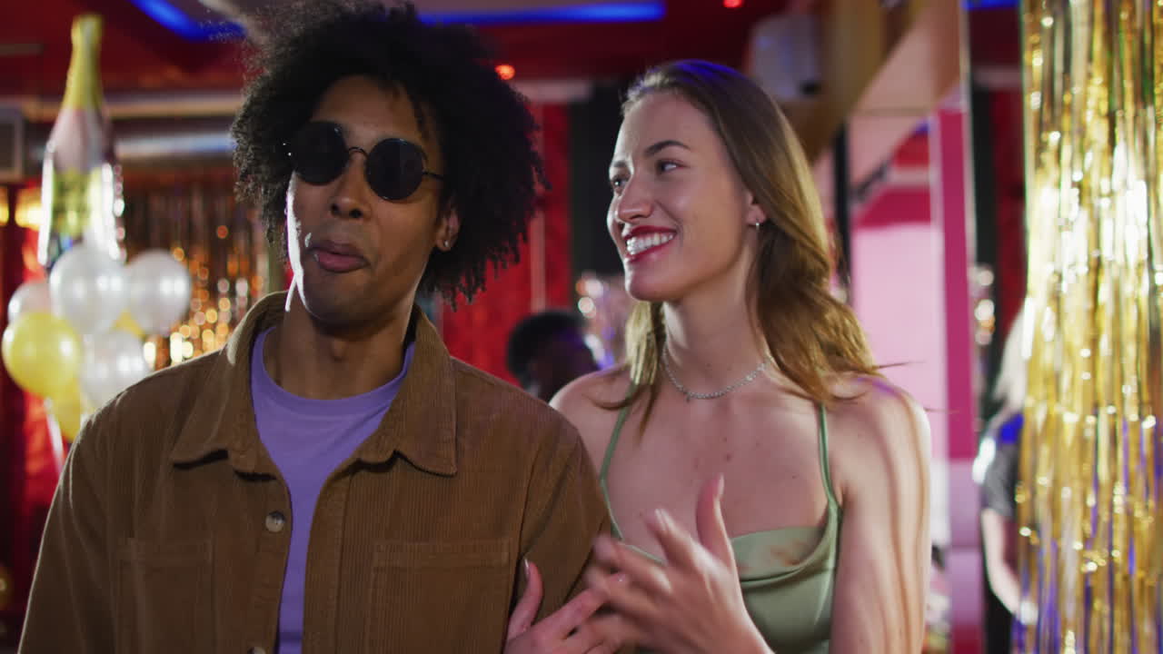Video of diverse happy couple walking into nightclub arm in arm talking
