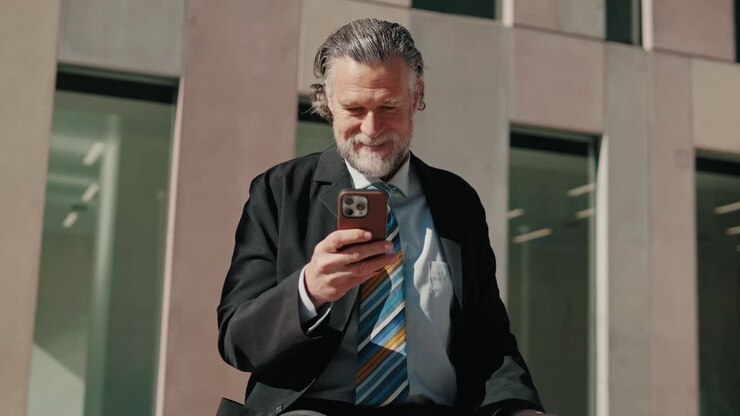 Happy Senior Businessman Using Smartphone Outdoors