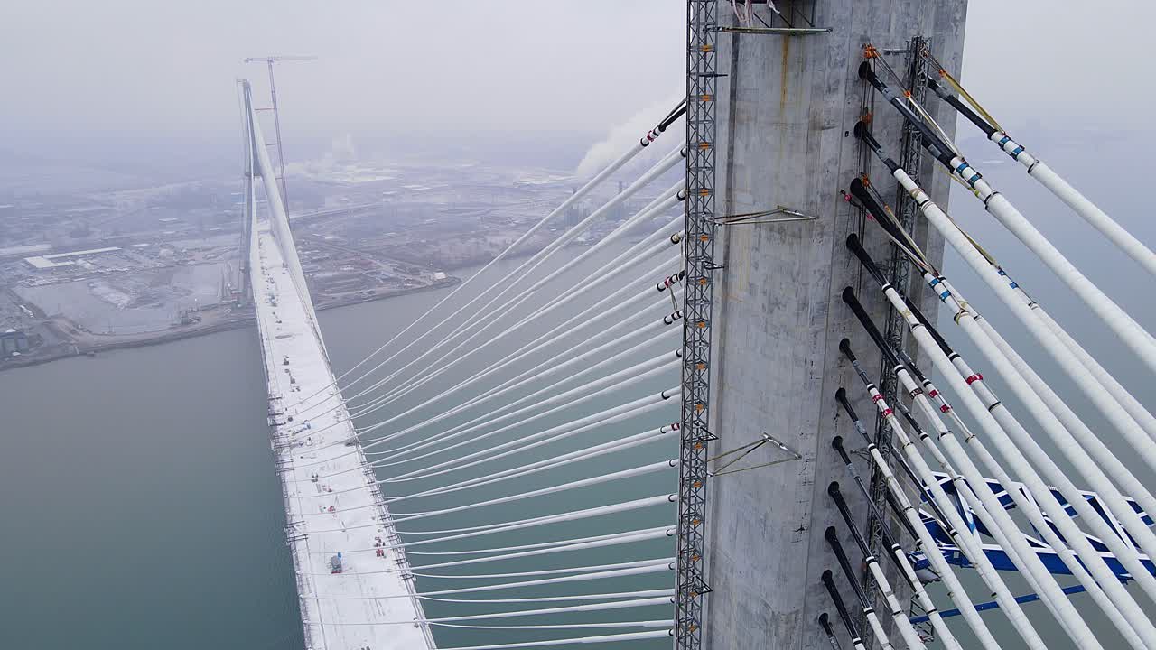 Aerial video of Gordie Howe International Bridge tower with cable anchors. Gordie Howe Bridge still under construction in winter.