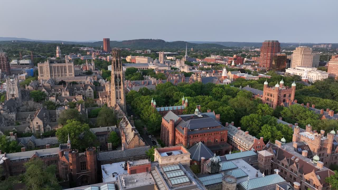 Historic town of New Haven in Connecticut, USA. golden sunset time in summer. Descend drone wide shot. Gothic Yale university and tower buildings in center. Downtown complex in distance. Brick gothic