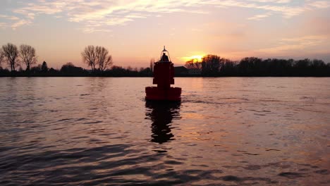 low aerial flying past floating buoy in river against sunet skies