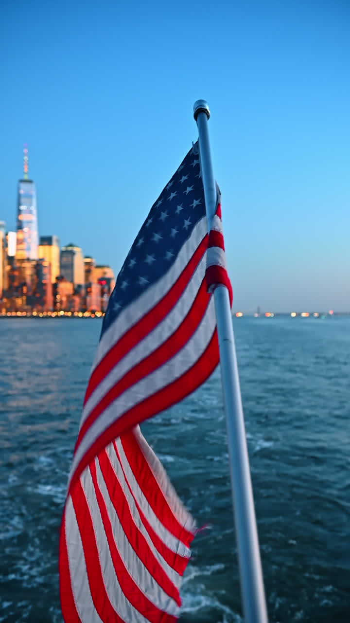 Bandiera americana sul traghetto a New York. La bandiera degli Stati Uniti sventola sul retro di un traghetto. Lo skyline di Manhattan è visibile in lontananza
