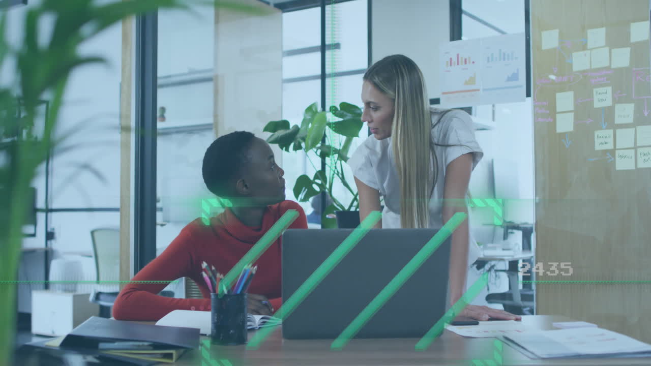 Two women collaborating at office desk with digital data overlay animation