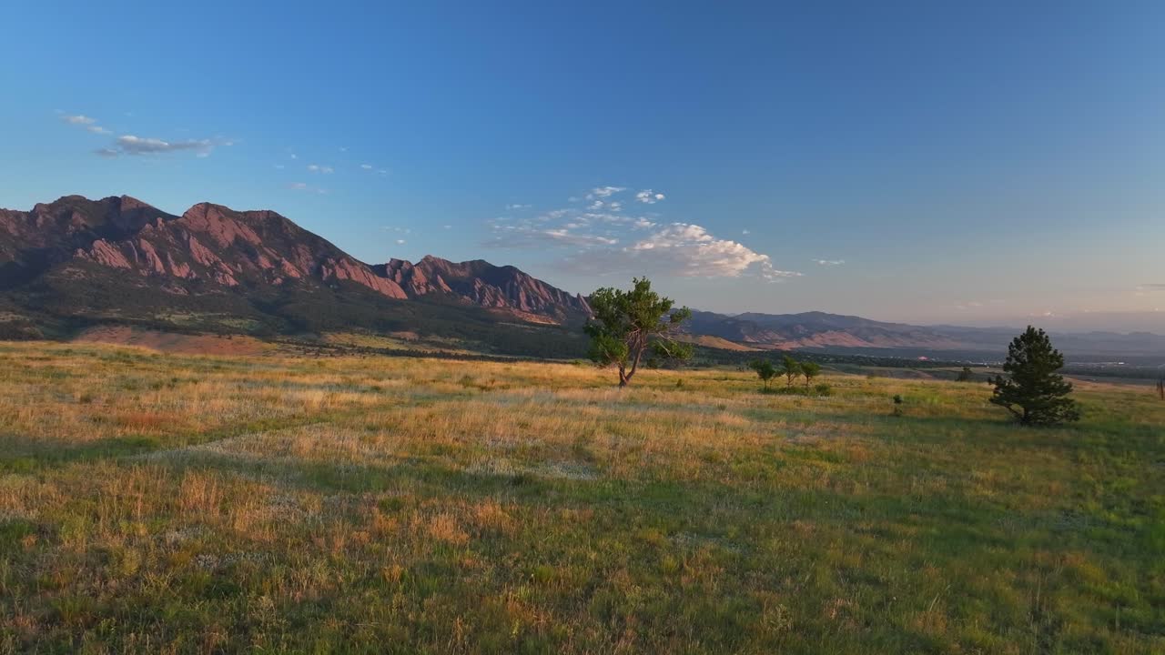 Greenbelt Plateau Flatirons Front Range Boulder Creek neighborhood Chautauqua Park morning sunrise aerial drone Colorado spring summer first light red slanted Rocky Mountains Pikes Peak pan left