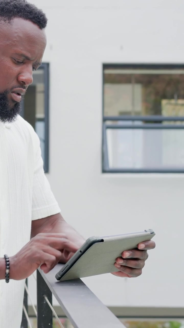 Vertical video: Holding tablet, man in white shirt tapping on balcony railing, bracelet, copy space