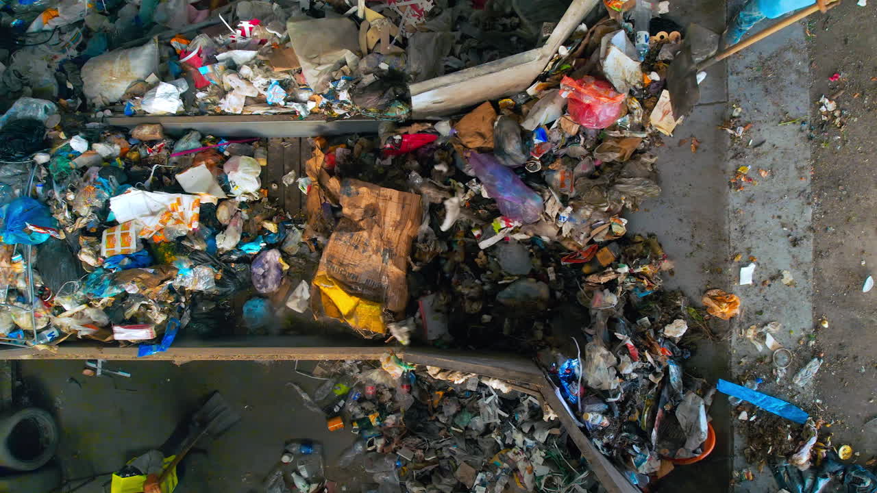 Workers loading garbage onto a conveyor belt at waste sorting plant. Slow motion