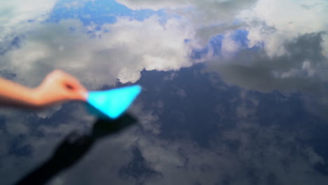 hand and paper boat in river. female hand starts in a stream the small paper ship