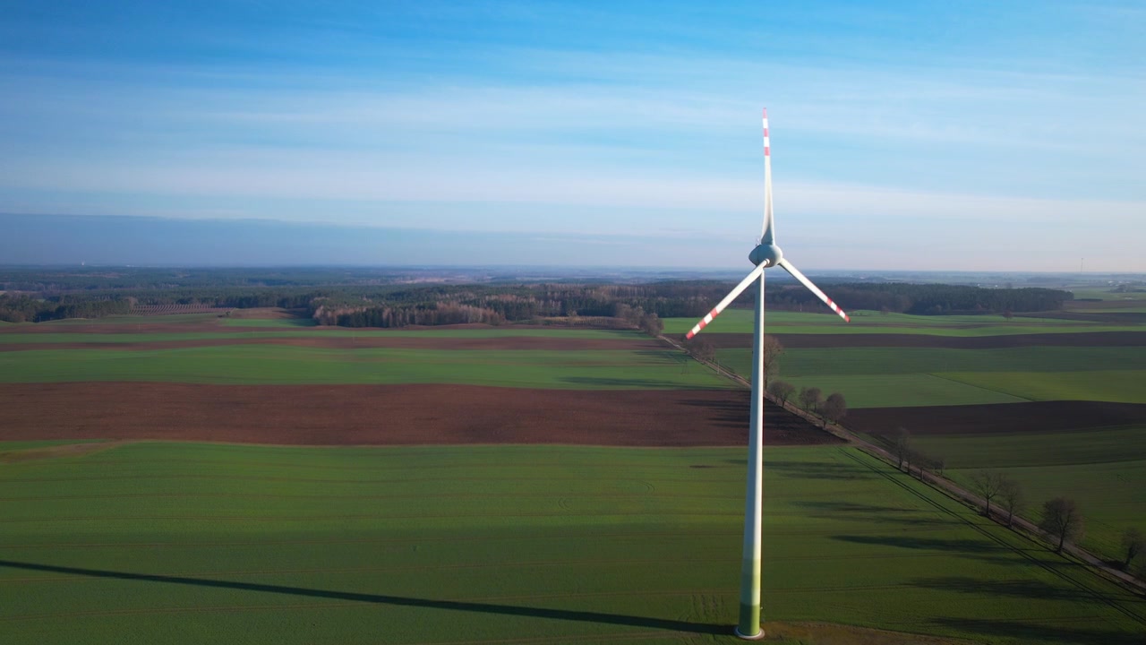Aerial forward flight towards Spinning windmill on rural field during sunlight