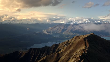 La-Luz-Del-Sol-Brilla-En-Las-Montañas-Durante-El-Amanecer,-Hermosas-Colinas-Con-Nieve-Sobre-Un-Valle-Con-Un-Río-Que-Atraviesa