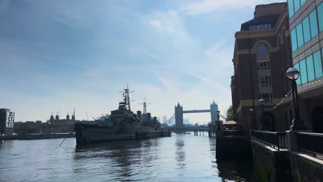 london warship on river thames with tower bridge view