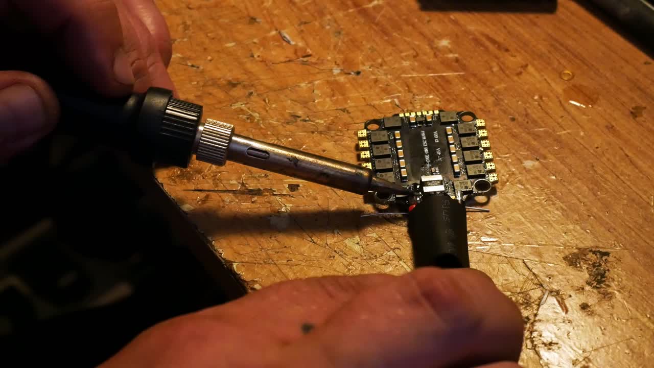 Close up preparing wiring soldering for FPV drone hobby build on the controller circuit board