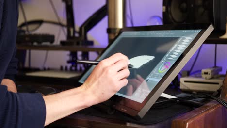 A-freelance-digital-artist-or-designer-sketching-and-painting-in-brushstroke-with-a-drawing-graphic-tablet-and-pen-in-an-art-studio