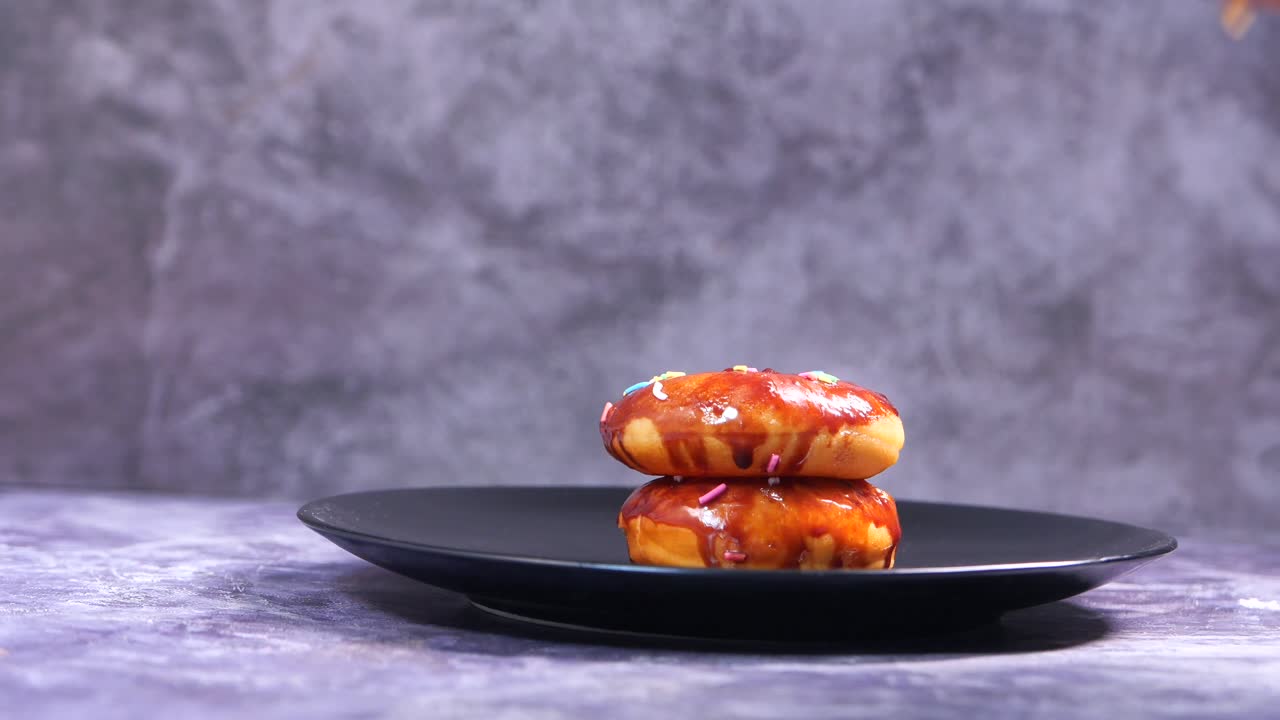 la mano recogiendo una rosquilla de chocolate de una pila de tres