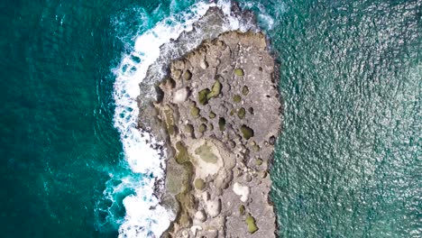 Puerto-Rico-isolated-rock-island-ocean-splashing-against-rocks-from-above-with-drone