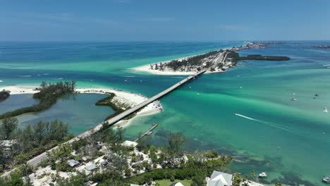 Aerial footage of Coquina Beach, Florida, featuring turquoise waters and sandy shores. Traffic flows on the bridge, enhancing the scene's vibrancy. Perfect for travel promotions. Florida , USA.