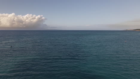 Aerial-view-of-surfer-ride-electric-surfboard-on-calm-Pacific-Ocean,-Maui