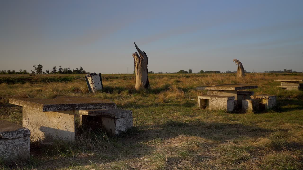 Wide view of a dilapidated rest area at the side of a route at sunset, wit a truck passing by.