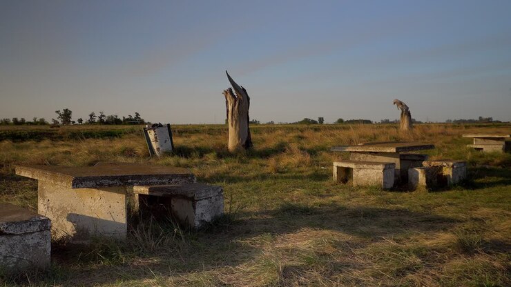 Wide view of a dilapidated rest area at the side of a route at sunset, wit a truck passing by.