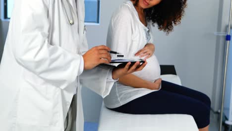 médico que muestra un informe médico a una mujer embarazada