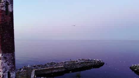 cinematic aerial shot of small island with old lighthouse, camera fly back