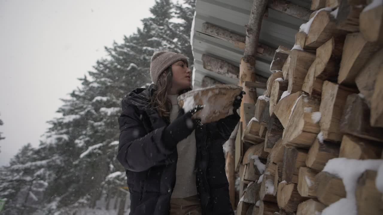 mujer poniendo leña en un cobertizo en invierno