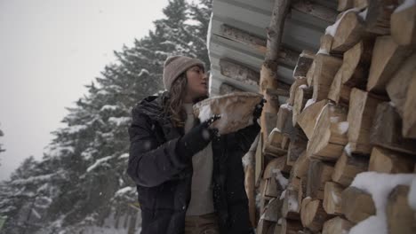 female putting firewood in shed in winter