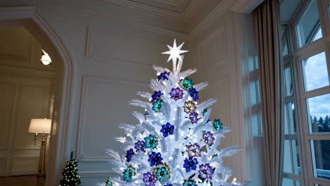 Sparkling white Christmas tree gleaming with vibrant ornaments, adorning luxurious interior featuring warm lighting and sophisticated architectural elements