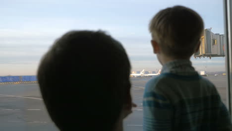 father and son looking out the window at airport